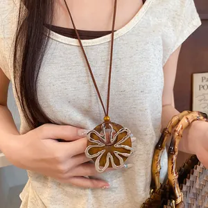 Vista detallada de un collar coreano con colgante floral de madera y plata en modelo