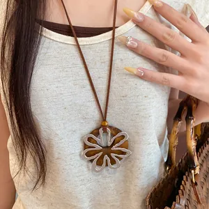 Detalle de collar con colgante de flor de metal sobre base de madera