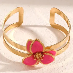 Detalle de un elegante brazalete dorado con una flor de esmalte rosa en estilo vintage