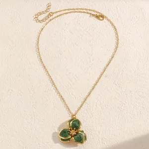 Detalle de collar con colgante de flor verde esmeralda vintage dorado