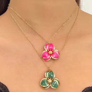 Detalle de collares dorados con colgantes de flores en esmalte vintage rosa y verde