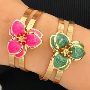 Primer plano de brazaletes dorados vintage con flores de esmalte rosa y verde vibrante