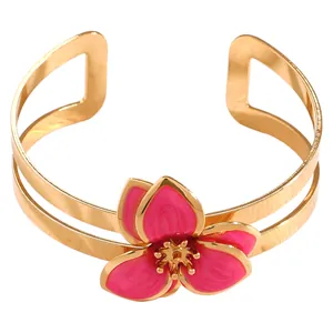 Primer plano detallado de un brazalete dorado vintage con una flor de esmalte rosa vibrante.