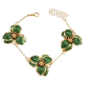 Vista detallada de una pulsera dorada con tres flores de esmalte verde vintage
