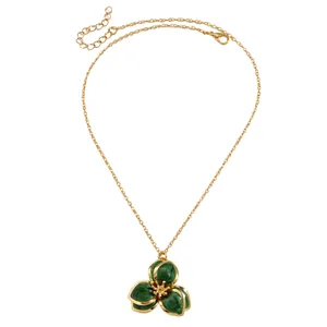 Detalle del colgante de flor veteada verde vintage en un collar de tono dorado