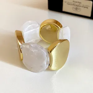 Close-up detail of a modern irregular geometric bangle featuring gold and white marble resin