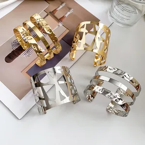 Detailopname van goud- en zilverkleurige golvende en geometrische opengewerkte armbanden
