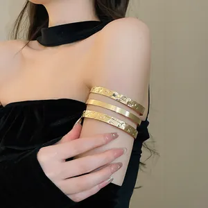 Detailweergave van een goudkleurige bovenarmband met drie lagen en gehamerde textuur
