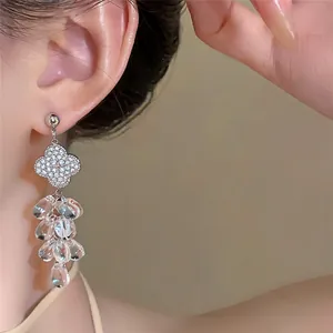 Primer plano de pendientes colgantes de trébol plateado con borlas de cristal