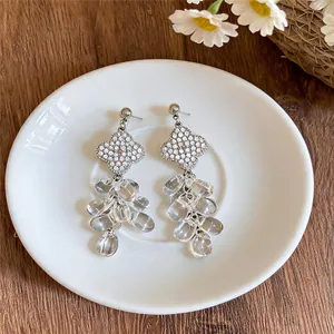 Detalle de elegantes pendientes de trébol con borlas de gotas de cristal transparente