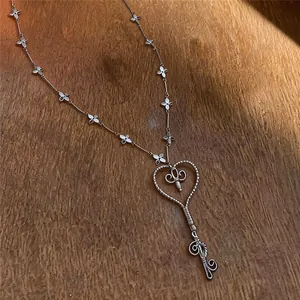 Detalle de un collar vintage plateado con colgante de llave en forma de corazón.