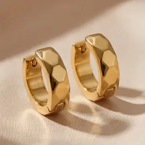 Macro view of gold-plated titanium steel hoop earrings with faceted rhombus texture.