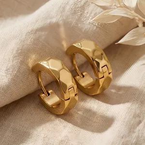 Macro view of gold titanium steel hoop earrings with faceted rhombus surface texture