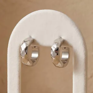 Close-up of 13mm diamond-faceted titanium steel hoop earrings on a white display stand