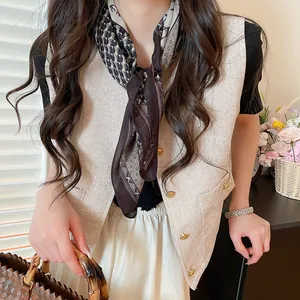 Gros plan d'un foulard carré rétro à motifs cachemire porté avec un gilet en tweed.
