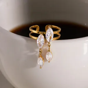 Adjustable gold titanium steel ring with marquise-cut dangling zircons on white cup rim.
