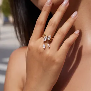 Close-up of a gold stainless steel ring with dangling marquise-cut zircons on a finger