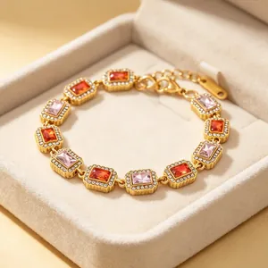 Detailopname van een gouden edelstalen armband met rode en roze rechthoekige zirkoon.