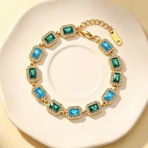 Detail van vintage gouden roestvrijstalen armband met groene en blauwe zirkonen