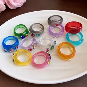 Kleurrijke dopamine stijl harsringen met sprankelende strass-steentjes op witte schotel.