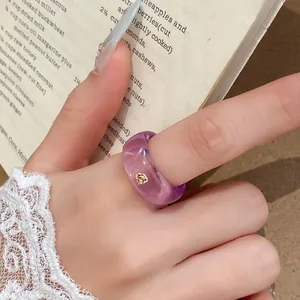 Detailopname van een paarse transparante harsring met een klein gouden strass-steentje.