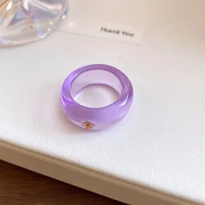 Gedetailleerde close-up van een paarse doorschijnende harsring met een oranje stras.