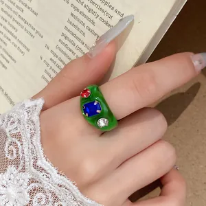 Detailopname van een groene hars ring met rode, blauwe en witte kristallen stenen