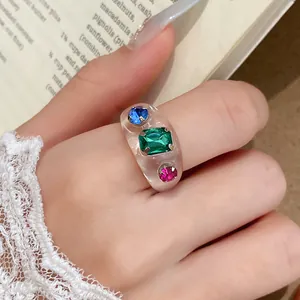 Close-up van een heldere harsring ingelegd met levendige blauwe, groene en rode edelstenen