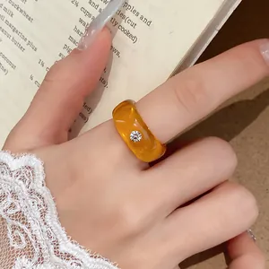 Detailopname van een amberkleurige harsring met sprankelend strass-detail