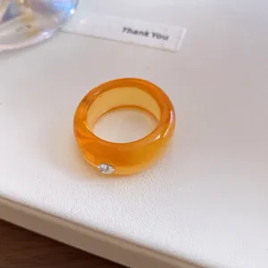 Close-up van een oranje harsring met een ingebedde sprankelende strassteen voor een zoete stijl