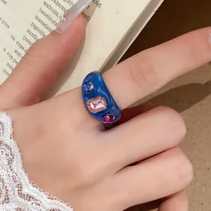Detailopname van een blauwe harsring met kleurrijke strass-steentjes in dopamine-stijl