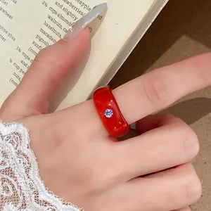 Gedetailleerde macro-opname van een rode harsring met een kleine paarse strass-inlay