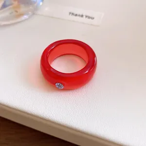 Macro-opname van een rode harsring met een klein paars strassteentje op een witte achtergrond