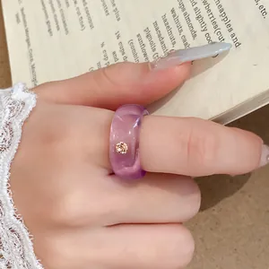 Detailopname van een paarse doorschijnende harsring met een strass op een vinger