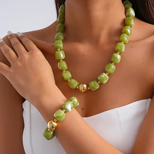 Detail view of green marbled acrylic necklace and bracelet set with gold accents