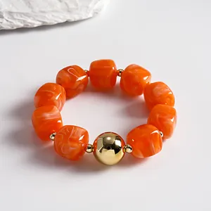 Chunky orange marbled acrylic bead bracelet featuring a central gold metallic sphere