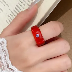 Detailweergave van een rode harsring met een centrale sprankelende strass-inleg.