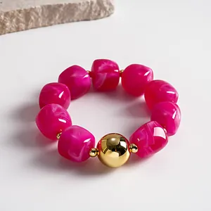 Close-up of fuchsia marbled acrylic bead bracelet with a large gold metal sphere