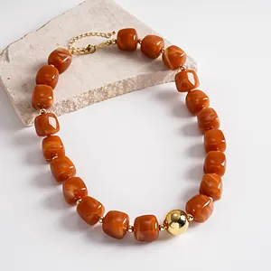 Detail view of chunky amber marbled acrylic beads and gold sphere on a vintage necklace