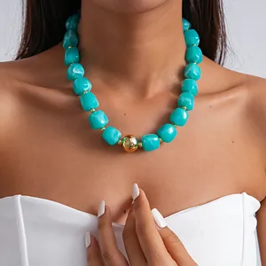 Chunky retro turquoise marbled acrylic necklace with gold bead worn by a model close-up.