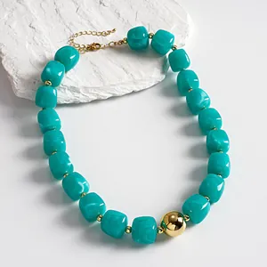 Detail view of chunky marbled turquoise acrylic necklace with a gold bead pendant.