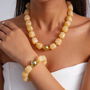 Detail view of chunky yellow marbled acrylic necklace and bracelet set with golden beads.