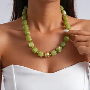 Close-up of green marbled acrylic necklace with a central gold sphere on a model