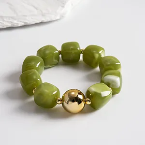 Detail view of vintage olive green marbled acrylic beads with a reflective gold sphere focal point