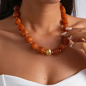 Close-up of retro chunky amber marbled acrylic bead necklace with gold ball on model