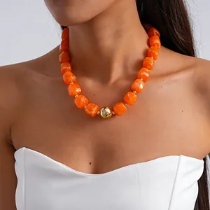 Close-up of orange marbled chunky acrylic necklace with a central gold metallic bead