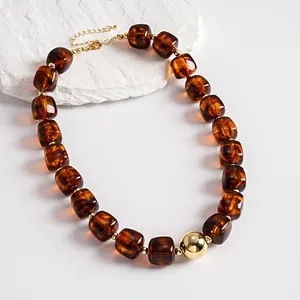 Close-up of vintage amber acrylic necklace with chunky gold central bead detail