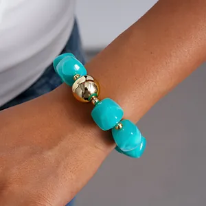 Close-up of a marbled turquoise acrylic bead bracelet with a central gold metallic sphere
