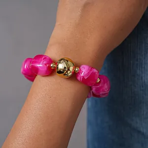 Close-up of chunky hot pink marbled acrylic beads and gold sphere on a stylish bracelet