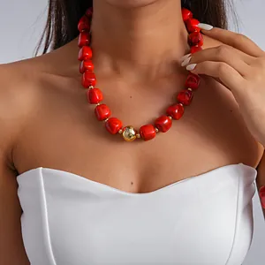Detail view of a chunky red marbled acrylic bead necklace with a gold accent sphere
